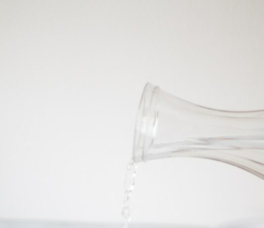 신체 리셋: 건강한 식단과 운동으로 새롭게 태어나는 법 A person pouring water into a glass on a table