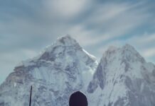 젊게 사는 비법 a man holding a rifle while standing on top of a mountain
