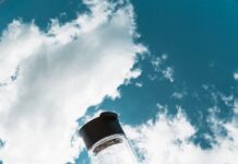 여름철 건강관리, 시원하고 안전하게 보내는 법 a hand holding a water bottle in front of a blue sky