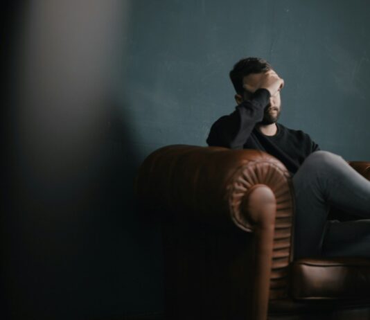 정신건강, 몸과 마음의 균형을 위한 첫걸음 a man holds his head while sitting on a sofa