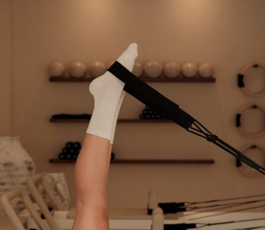 필라테스, 몸과 마음을 동시에 단련하는 현대인의 건강 비법 Woman does pilates exercise on a reformer machine.