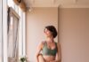 “필라테스, 몸도 마음도 튼튼하게… 현대인의 새로운 건강 루틴으로 자리잡아” a woman in a green sports bra top and leggings holding a yoga mat