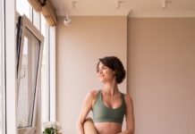 “필라테스, 몸도 마음도 튼튼하게… 현대인의 새로운 건강 루틴으로 자리잡아” a woman in a green sports bra top and leggings holding a yoga mat